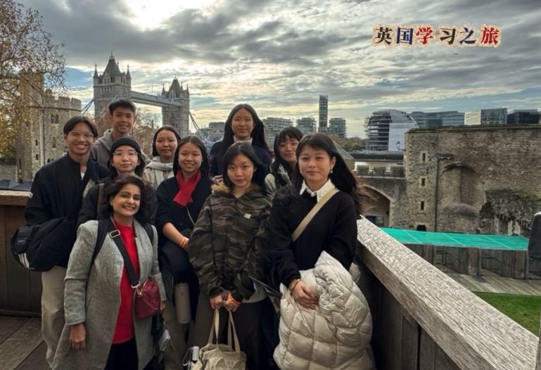 A group of students posing with Tower Bridge visible in the background during their UK learning journey.